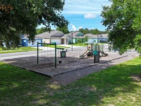 Eustis townhouse for rent - A playground with a slide and swings in a grassy area.