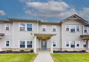 Covington townhouse for rent - A two-story residential building with a front yard and a clear sky.