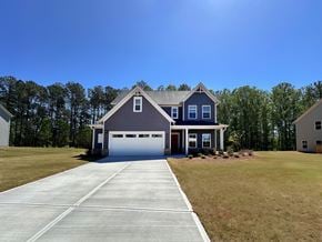 Winder apartment for rent - A two-story house with a garage is surrounded by a grassy area and trees.