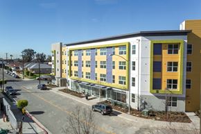 San Diego apartment for rent - a building with a yellow and white facade and a parking lot