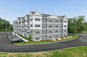 Derry apartment for rent - A large, modern apartment building with a parking lot in front.