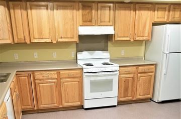 Lake Ariel apartment for rent - A kitchen with wooden cabinets and a white stove top oven.