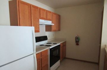 Mount Pocono apartment for rent - A kitchen with a white fridge, black stove and wooden cabinets.