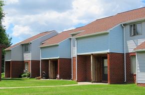 Elysburg apartment for rent - A row of houses with a red brick base and grey roofs.