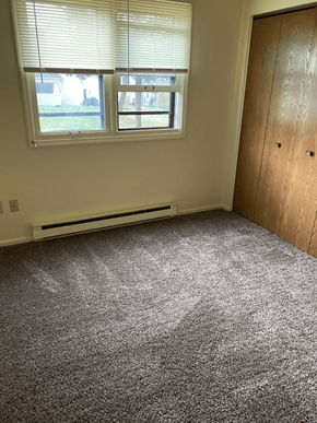 Pine Grove apartment for rent - A room with a carpeted floor, a window with blinds, and a wooden door.
