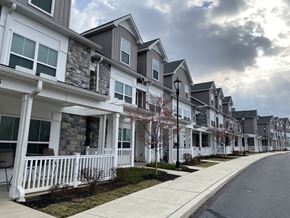 Mechanicsburg apartment for rent - A row of houses with white fences and green trees.