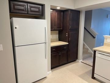 Mechanicsburg apartment for rent - A white refrigerator stands in a kitchen with dark brown cabinets.