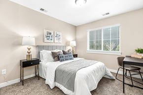 Chesterfield apartment for rent - A bedroom with a bed, a chair, and a table with a lamp on it.
