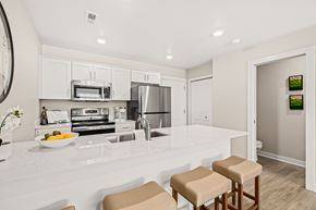 Shelby Township townhouse for rent - A kitchen with white countertops and stools.