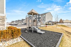 Sterling Heights apartment for rent - A playground with a slide and a swing set in the foreground and apartment buildings in the background.