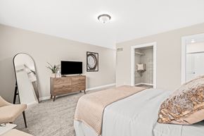 Shelby Township townhouse for rent - A bedroom with a bed, chair, and a dresser with a mirror.