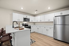Shelby Township townhouse for rent - A modern kitchen with white cabinets and a stainless steel refrigerator.