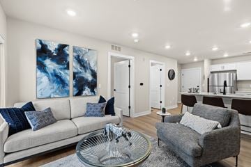 Shelby Township townhouse for rent - A modern living room with a grey couch, a glass coffee table, and a large abstract painting on the wall.