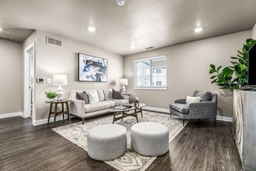 Sterling Heights apartment for rent - A living room with a grey couch, a grey armchair, a grey ottoman, a wooden coffee table, and a painting on the wall.