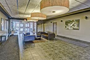 Airdrie apartment for rent - A spacious waiting area with a bench, a table, and a painting on the wall.