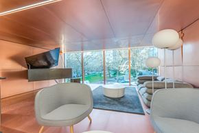 Vancouver condo for rent - A modern living room with a television, two chairs, and a table.