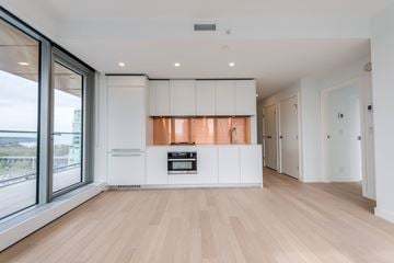 Vancouver condo for rent - A modern kitchen with white cabinets and a wooden floor.