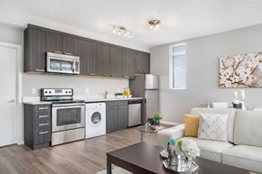 Calgary apartment for rent - a living room with a white couch and a kitchen with stainless steel appliances