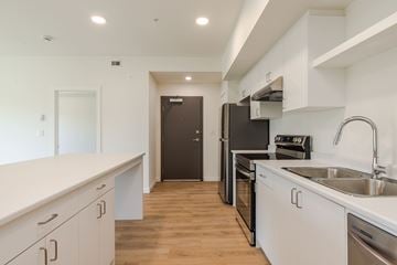 Campbell River apartment for rent - A kitchen with white cabinets and a black refrigerator.