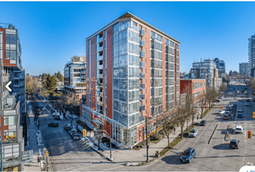 Vancouver apartment for rent - A tall red and white building is in the middle of a city street.