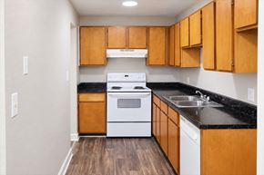Charlotte apartment for rent - A kitchen with wooden cabinets and a white stove top oven.