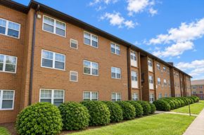 Charlotte apartment for rent - A row of red brick apartment buildings with green bushes in front.