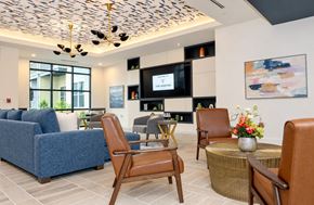 Charlotte apartment for rent - A living room with a blue sofa, a wooden chair, and a television.