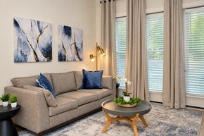 Charlotte apartment for rent - A living room with a beige couch, a coffee table, and two abstract paintings on the wall.