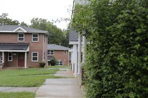 Charlotte apartment for rent - A house with a red door is surrounded by greenery.