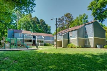 Charlotte apartment for rent - A playground area is located in front of a building with a green lawn.
