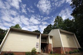 Charlotte apartment for rent - A beige building with a red brick base and a balcony on the second floor.