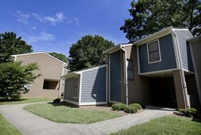 Charlotte apartment for rent - A small building with a grey roof and a white door is surrounded by a grassy area.