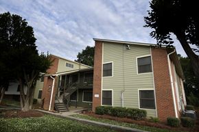 Charlotte apartment for rent - A two-story apartment building with a green siding and a brick base.
