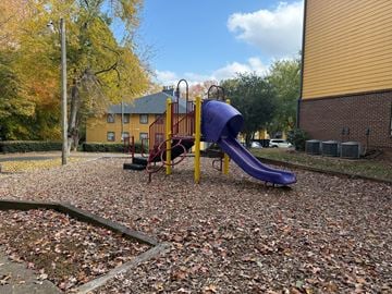 Charlotte apartment for rent - A playground with a purple slide and a yellow and red swing set.