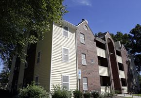 Charlotte apartment for rent - A building with a yellow siding and a brick section with a white sign on it.