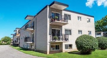 Chatham apartment for rent - A modern apartment building with balconies and green bushes in front.