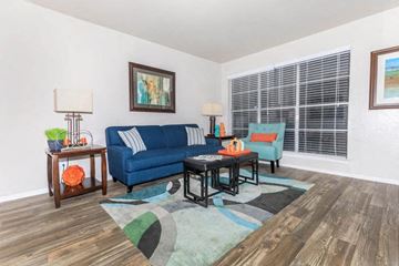 San Antonio apartment for rent - A living room with a blue couch and a table with a lamp on it.