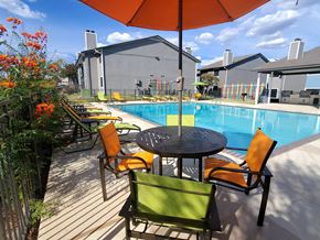 Austin apartment for rent - A table with chairs and an umbrella is in front of a pool.
