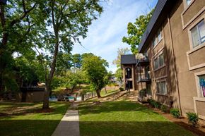 Atlanta apartment for rent - A tree-lined walkway leads to a building with a balcony.