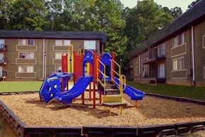 Atlanta apartment for rent - A playground with a blue slide and yellow and red play structure in front of apartment buildings.