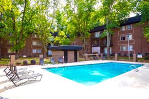 Atlanta apartment for rent - A swimming pool surrounded by trees and chairs in front of apartment buildings.