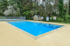 Atlanta apartment for rent - A blue swimming pool surrounded by a fence and trees.