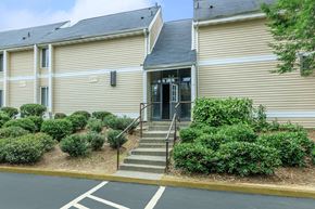 Atlanta apartment for rent - A building with a beige facade and a black roof with a set of stairs leading up to the entrance.