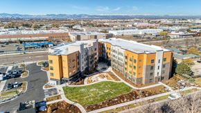 Aurora apartment for rent - A large multi-story building with a parking lot in front.