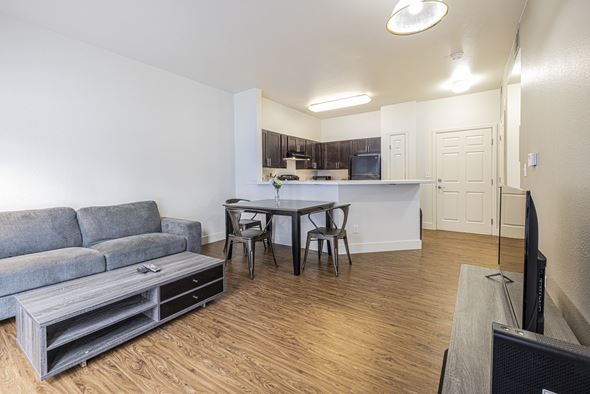 Aurora apartment for rent - A living room with a couch, coffee table, dinette, tv on an entertainment staff, with a view of the kitchen