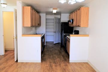 Aurora apartment for rent - an empty kitchen with wood flooring and wooden cabinets