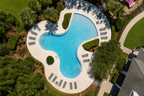Pensacola apartment for rent - A swimming pool surrounded by trees and a concrete patio.