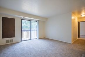 Grand Rapids apartment for rent - A room with a carpeted floor, a window with blinds, and a sliding glass door leading to a balcony.