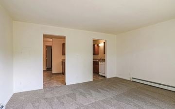 Grand Rapids apartment for rent - A room with a carpeted floor and a kitchen visible through a doorway.