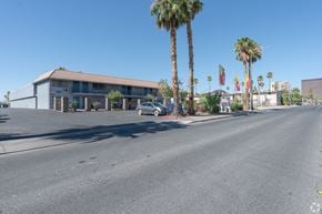 Las Vegas apartment for rent - A street view with an apartment building, palm trees, and a car.